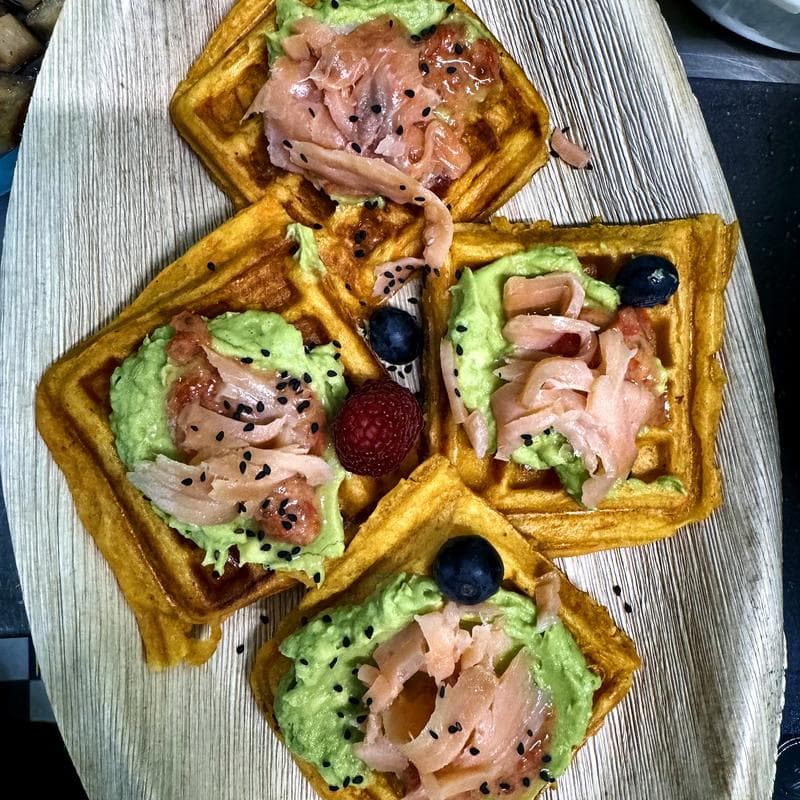 Süßkartoffelwaffeln mit Avocadocreme und Räucherlachs auf Palmblatt